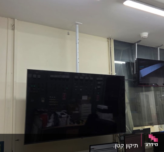 מסך טלוויזיה מותקן על קיר עם כלי עבודה על שולחן